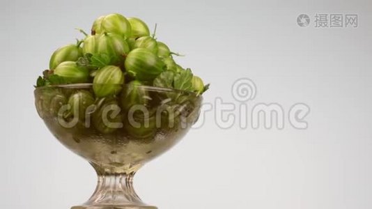 旋转玻璃花瓶与一堆绿色的鹅莓。视频