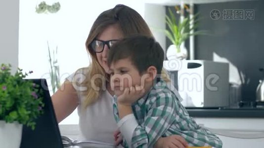 远距离学习，孩子和妈妈一起做作业，坐在桌子旁，厨房里有笔记本电脑视频