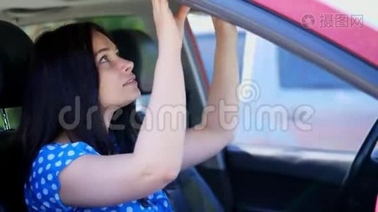 美丽的黑发女人坐在车里，照着镜子，把发型理直气壮地化妆视频