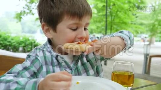 有害的食物，五岁的男孩在户外的一张桌子上坐着一片比萨饼视频