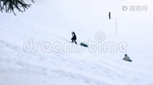 孩子们在冬季公园的油管里从雪山上骑马。视频