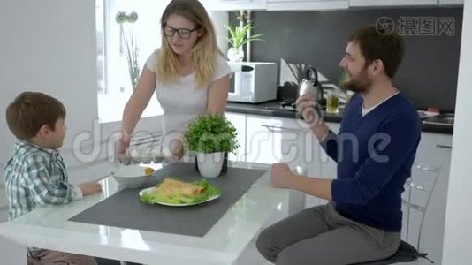 一家人的早晨，妈妈把鸡蛋放在桌子上喂丈夫和儿子视频