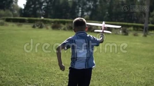男孩在阳光明媚的天气在公园里发射一架玩具飞机，心情很好。 慢动作。视频