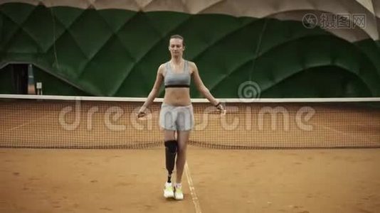 一个美丽勇敢的女孩正在网球场上用跳绳努力练习。 右脚的假肢是视频
