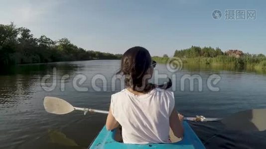 阳光明媚的一天，女人在河上皮划艇。视频