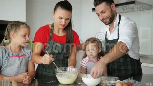 父母教孩子做饭。 他们教孩子们如何烹饪面团。视频