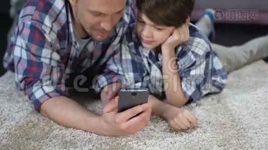 父亲在智能手机上展示儿子有趣的应用程序，花时间在一起视频