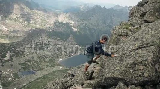 一个勇敢的年轻男性登山者在岩石上攀爬。视频