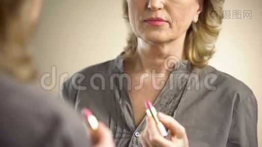 退休妇女在镜子前涂粉红色口红，防老化妆品视频