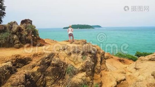 女孩旅行者站在海边的岩石上。 热带岛屿视频