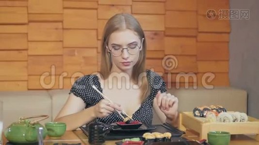 日本餐馆里的一个年轻女孩吃寿司，给她们蘸酱油视频