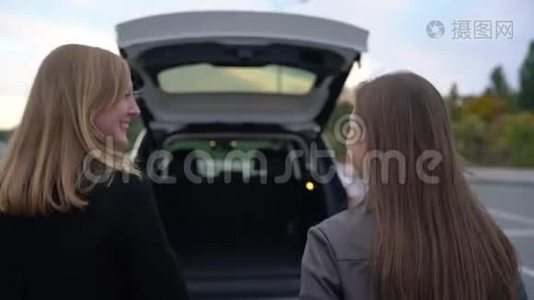 两个快乐的女人购物后，把包放在车的后备箱里，坐在里面，准备开车离开视频