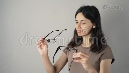 年轻女子在灰色背景的镜子里检查她的新眼镜。 戴着灰色眼镜的年轻女子视频