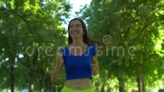 女跑步者在公园户外锻炼时慢跑。视频