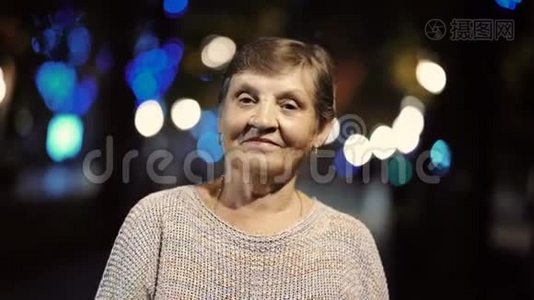 美丽的肖像，微笑的老年妇女在夜晚，灯光照亮街道。 高加索地区的祖母视频