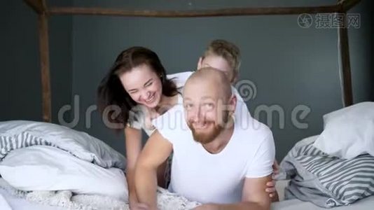 年轻女子带着儿子和丈夫在床上放松，非常幸福的家庭时刻视频
