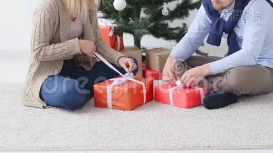 圣诞节和新年的概念。 快乐的年轻夫妇打开圣诞礼物视频
