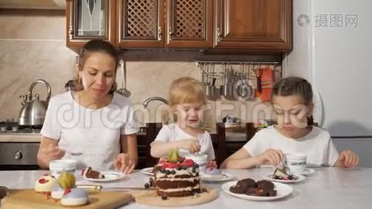 妈妈和两个女儿正在厨房里喝一杯带自制巧克力蛋糕的茶，家里过生日。视频