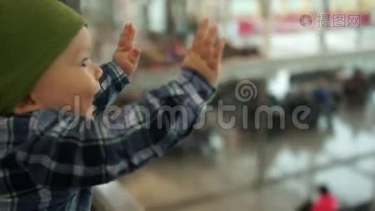 一岁的孩子用钢笔敲玻璃，看着机场候车室。 父亲抚养孩子视频