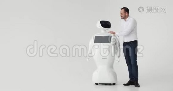 男人抚摸机器人。 和机器人的友谊。 现代机器人技术。 一个男人和一个机器人交流，视频