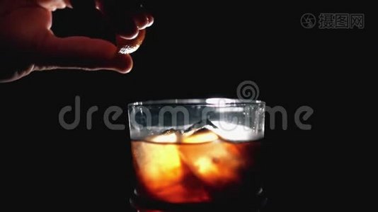 将石灰或柠檬挤在新鲜水果鸡尾酒上。 威士忌和可乐在深色背景和室内灯光下加冰块视频