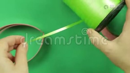 女剪刀在绿色背景上剪绿色丝带。视频