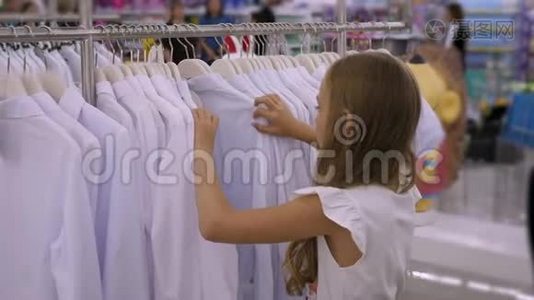 在服装店里挑选白色衬衫的少女。 时尚和购物视频