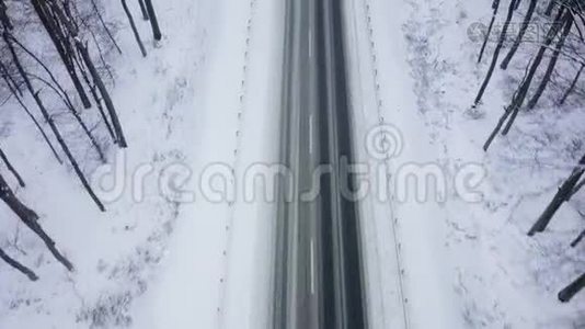 在降雪的冬季森林包围的道路上卡车行驶的鸟瞰图视频