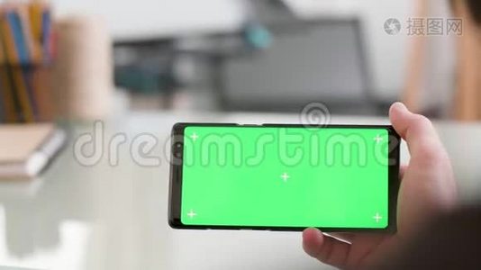 一个手持绿色屏幕的智能手机的人视频
