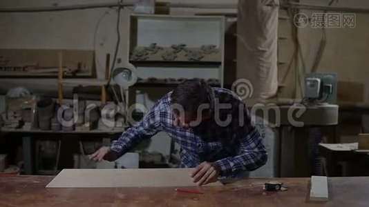 木工在桌面上用砂纸打磨木板.. 木工车间的工作视频