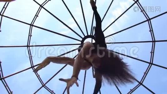 从底部看，女孩做的麻绳倒挂在环上进行空中杂技视频