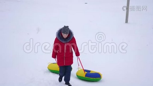 少女手持雪碟爬上雪山。 新鲜空气中的冬季游戏。 圣诞节视频