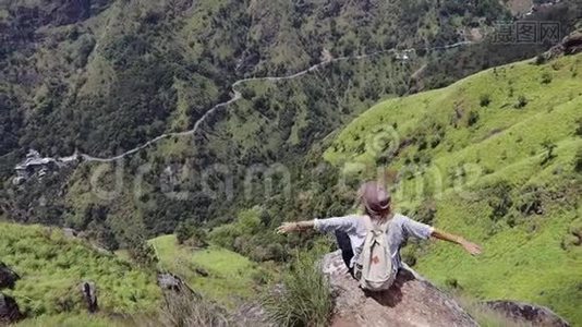 女旅行者坐在山上的大石头上。视频