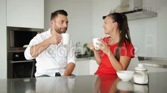 可爱的年轻夫妇在厨房里喝咖啡。 他们今天早上心情不错。视频