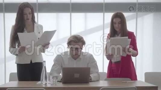 戴眼镜的金发男人坐在一间舒适的办公室里，桌上放着上网本，同事在上面签文件视频