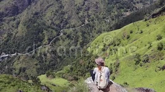 女旅行者坐在山上的大石头上。视频
