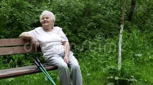 老奶奶坐在公园的长凳上休息视频