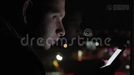 年轻人晚上在模糊的城市灯光面前使用智能手机手机应用技术。视频
