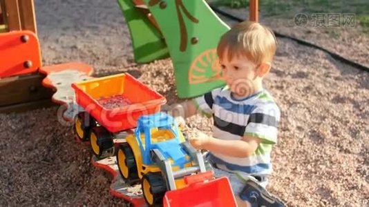 4k视频小集中幼儿男孩玩拖车和装载机在沙箱视频