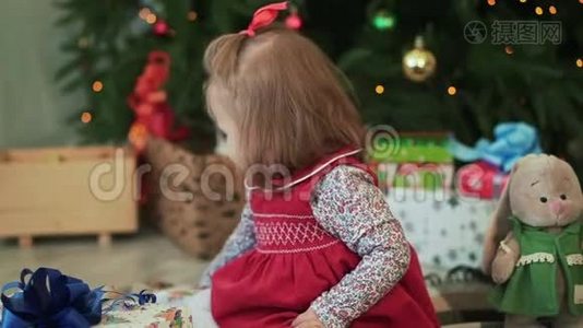 可爱的小女孩给父母送圣诞礼物，坐在圣诞树旁。特写。视频