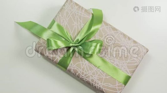 女人的近景`她的手在现盒上系了一个蝴蝶结，用漂亮的纸把礼物包起来。视频
