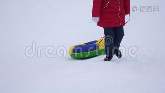 少女手持雪碟爬上雪山。 新鲜空气中的冬季游戏。 圣诞节视频