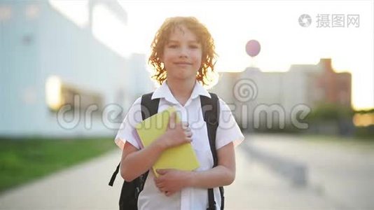 快乐可爱的聪明男孩手里拿着书包和书。 现代背包。 孩子准备回答。 第一次视频