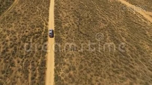 背面鸟瞰：大银色SUV在日落前的草原上行驶。视频