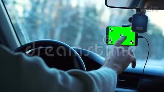 冬天开车的人。 智能手机有一个绿色的屏幕贴在挡风玻璃上，它把手指按在挡风玻璃上视频