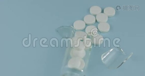 破碎的玻璃罐，里面有许多药丸和药物在蓝色背景下旋转视频