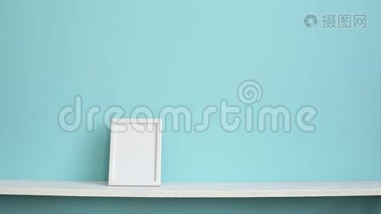 现代客房装饰与相框模型。 白色的架子，贴在青绿色的墙上，用手放下盆栽的龙葵视频