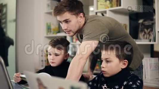 两个男孩和他们的年轻男性程序员老师在教室里学习如何使用笔记本电脑的录像。 替代办法视频