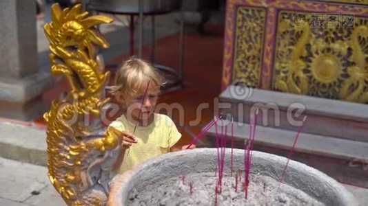 一个小男孩在佛寺里慢镜头，在香炉里放一根芳香棒视频