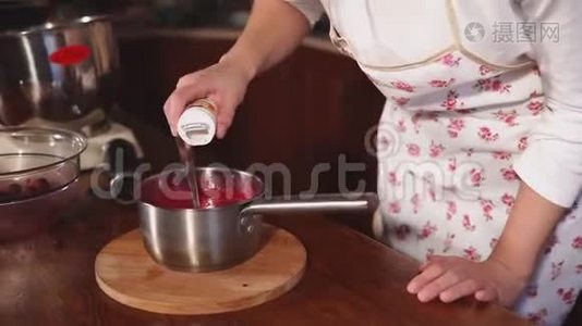在厨师的手`近距离拍摄，他把糖和红浆果酱混合在锅里视频